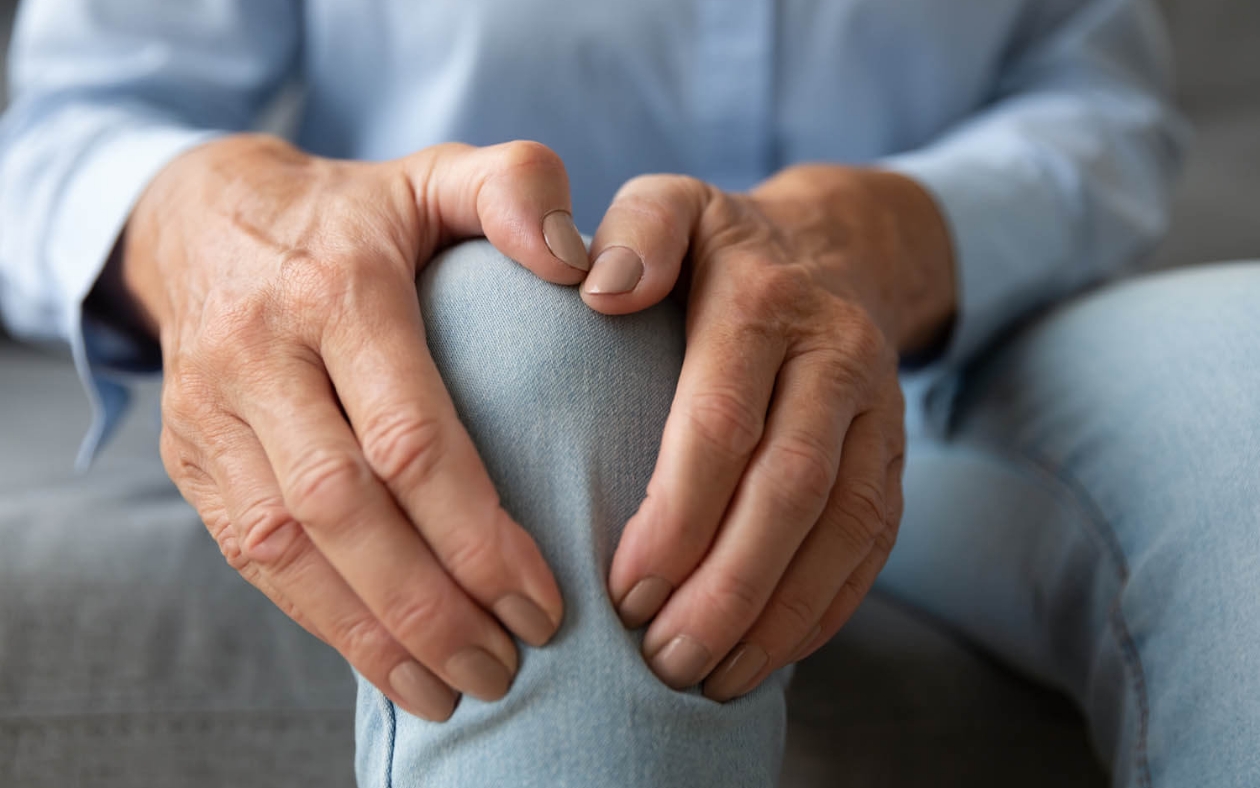 Hombre mayor sosteniendo su rodilla con ambas manos