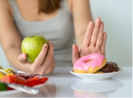 Mujer con manzana en mano y rechazando donas Mujer con manzana en mano y rechazando donas