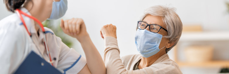 Médica chocando codos con una paciente mayor