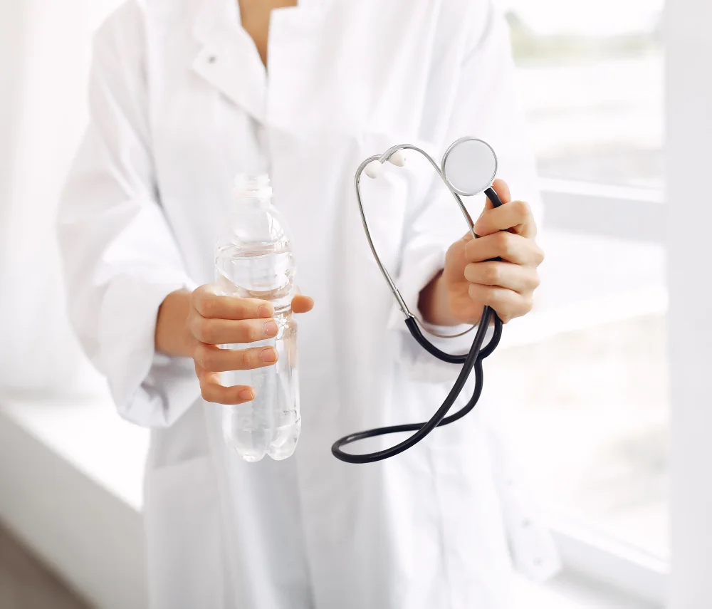 Una doctora con un estetoscopio y una botella de agua durante una asesoría en nutrición, destacando el rol de los nutriólogos para bajar de peso. Una doctora con un estetoscopio y una botella de agua durante una asesoría en nutrición, destacando el rol de los nutriólogos para bajar de peso.